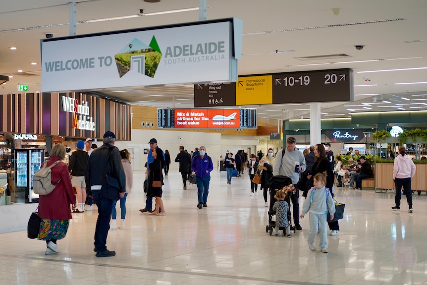 Gente caminando con maletas frente a tiendas en un aeropuerto