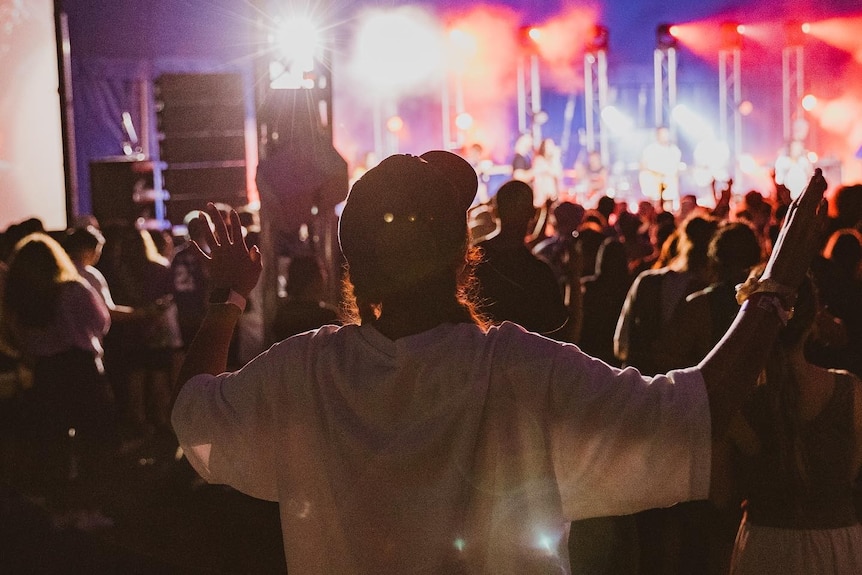 A person in front of a stage holding up two hands