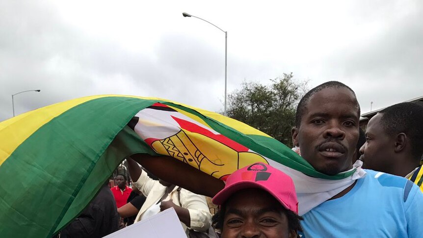 Two protesters against Robert Mugabe in Zimbabwe holding a "Bob's not your uncle" sign