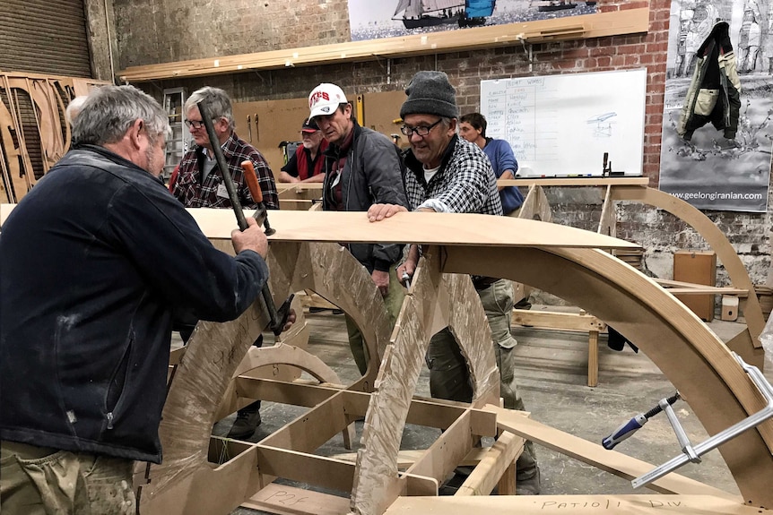 Four men from the Iraqi Syriac community working on the hull of a skiff at Geelong.