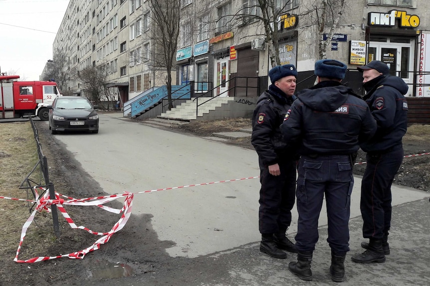 Tape seals a residential building while police stand together nearby.