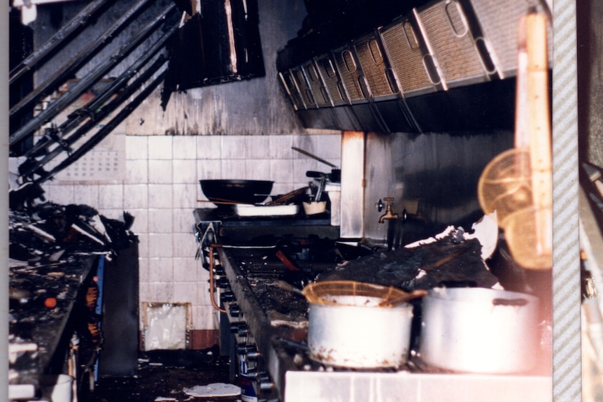 A black and charred kitchen of a restaurant that has been damaged by fire.