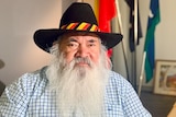 Image of an older Aboriginal man with a thick white beard, wearing a black hat.
