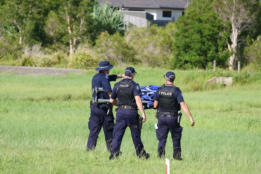 Three police officers walking on a grassy field.
