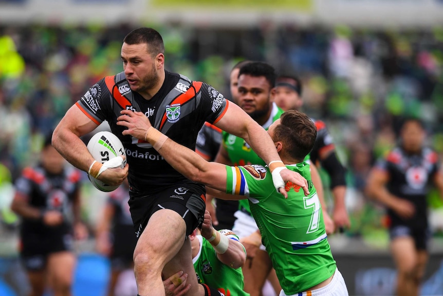 Lachlan Burr runs with the ball while shrugging off a would-be tackler.