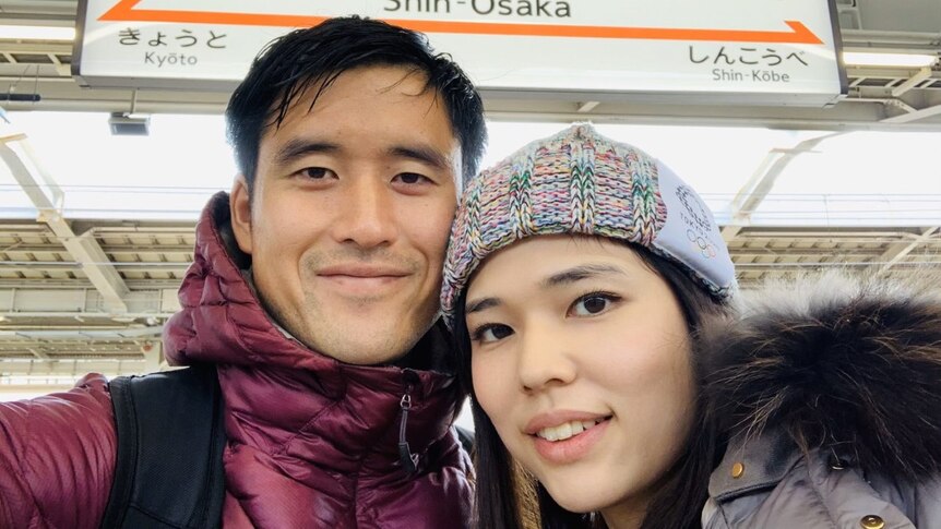 Un selfie d'un homme et d'une femme dans une gare japonaise. 