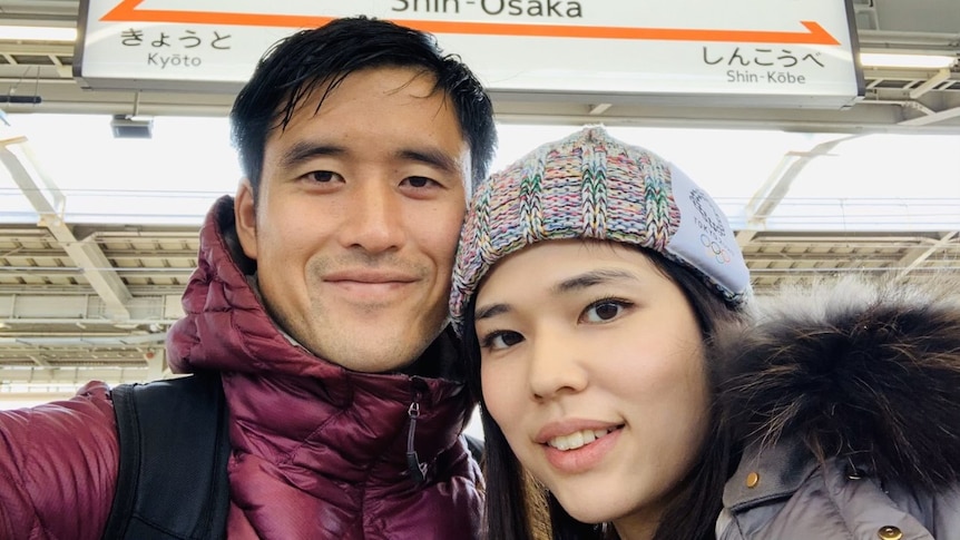 A selfie of a man and woman at a Japanese train station. 