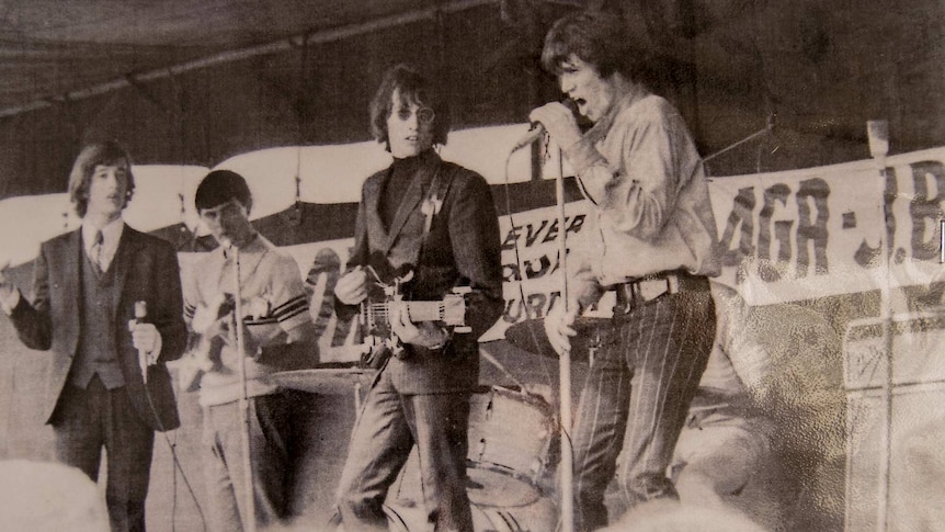 A black and white image of a band playing on a small stage