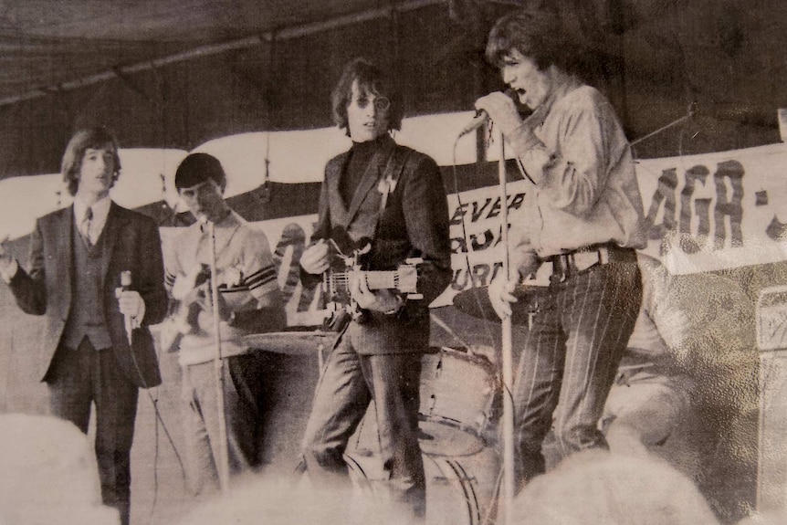 A black and white image of a band playing on a small stage