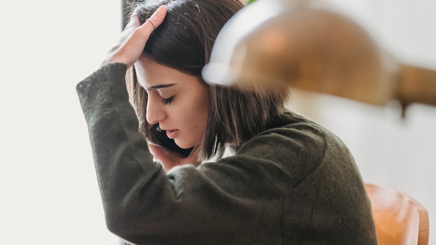 A woman runs her hand through her hair while on the phone