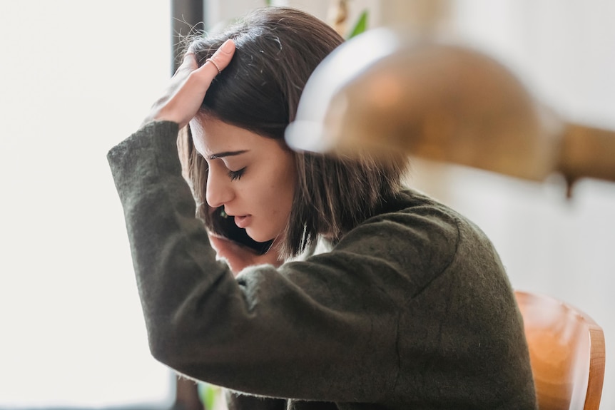 A woman runs her hand through her hair on the phone