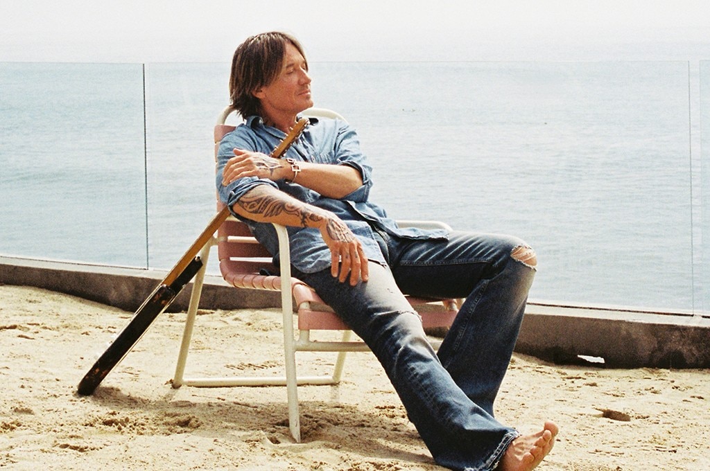Keith Urban with a guitar sitting down with eyes closed