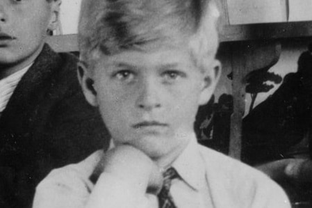 A black and white photo of a young blonde boy wearing a shirt and tie.