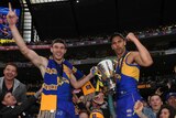Luke Shuey and Dom Sheed stand on the fence celebrating with the AFL premiership trophy at the MCG.
