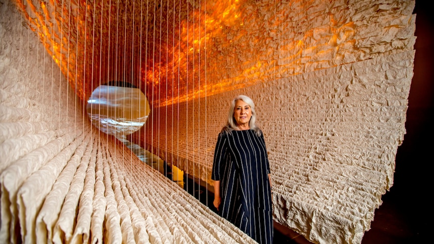 The arts patron standing inside a huge cylinder made of rows of rice paper.