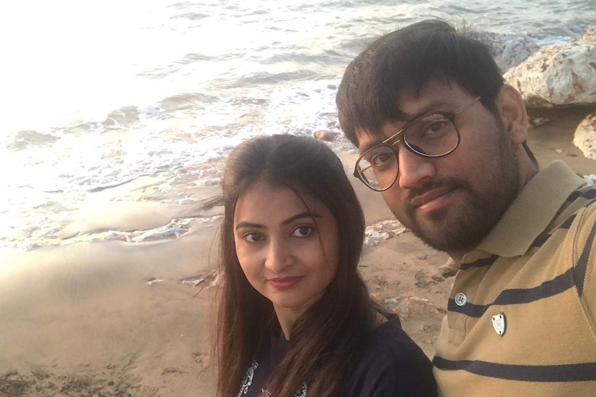 Asma Mukhi and her husband Salman look towards the camera, with a Darwin beach in the background.