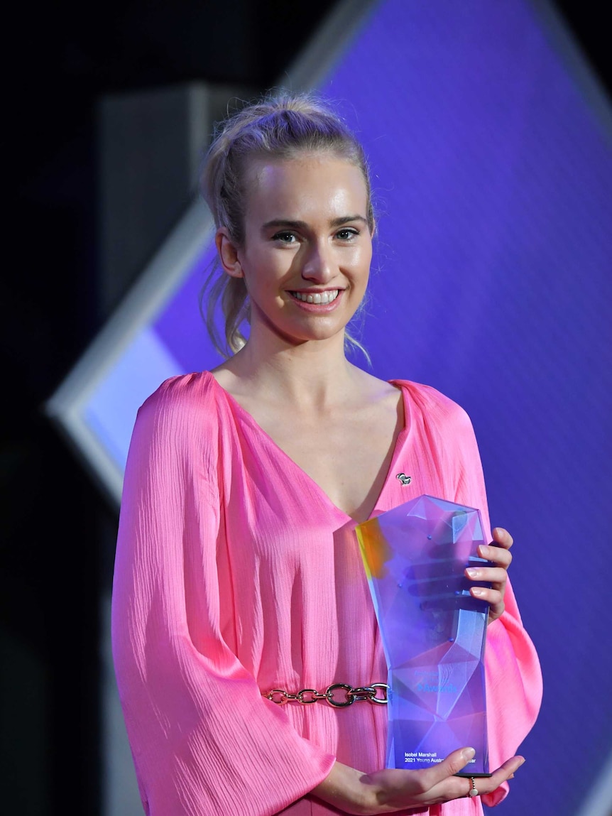 Isobel smiles, holding her award.