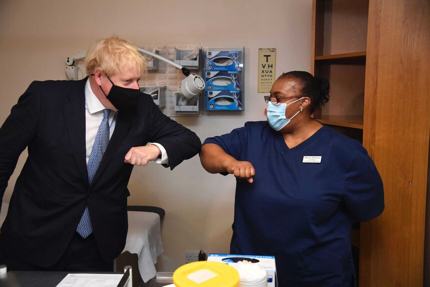 Boris Johnson touches a health worker in medical scrubs