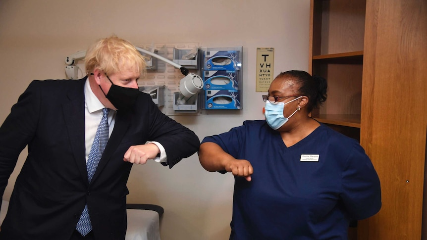 Boris Johnson touches elbows with a health worker dressed in scrubs