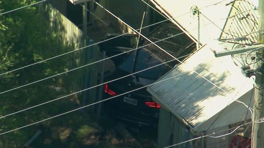 Aerial shot of black BMW that has crashed through a suburban fence