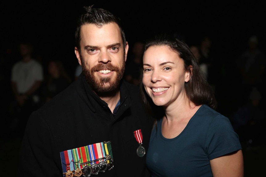 Close up shot of a woman and her brother smiling, the man wearing war medals.