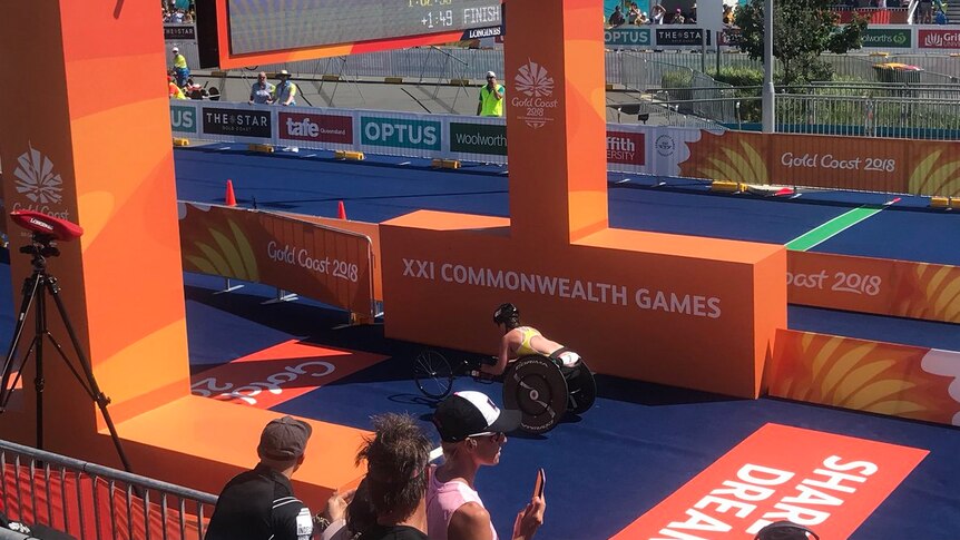 A female athlete crosses the finish line on a bike.