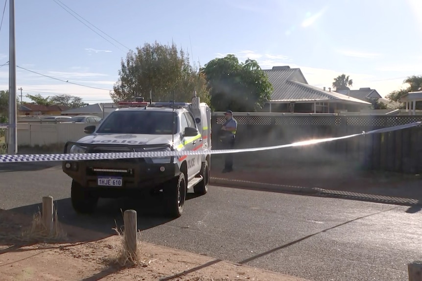 A police car and police tape cordoning off a road outside a house in suburban Carnarvon.