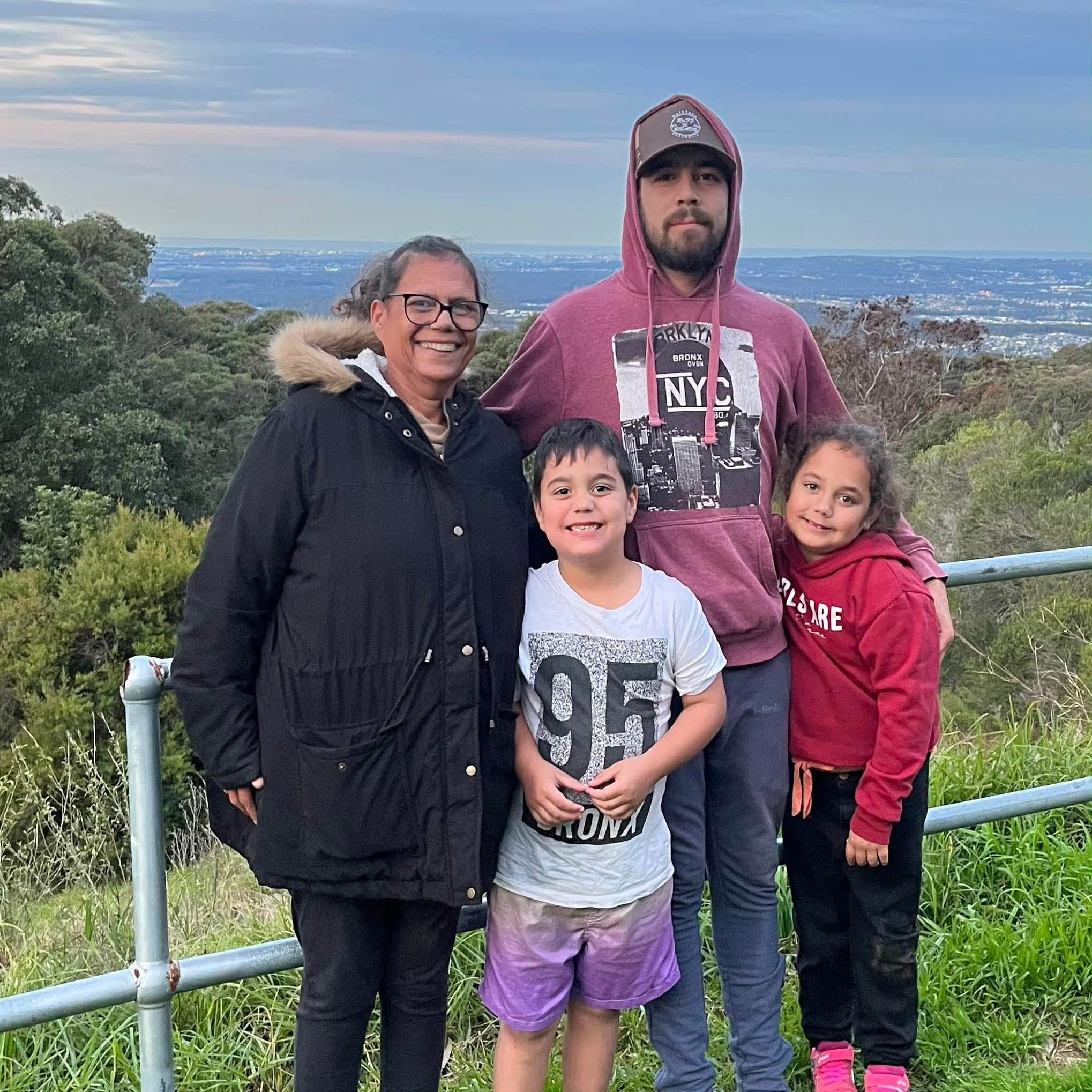 Un joven con una sudadera con capucha abraza a una mujer mayor y dos niños.