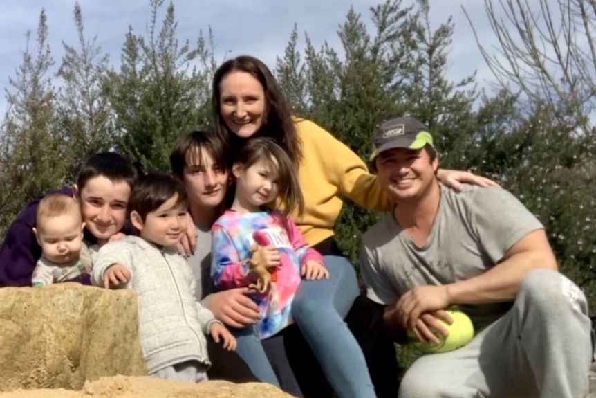 Family sits together in front of trees