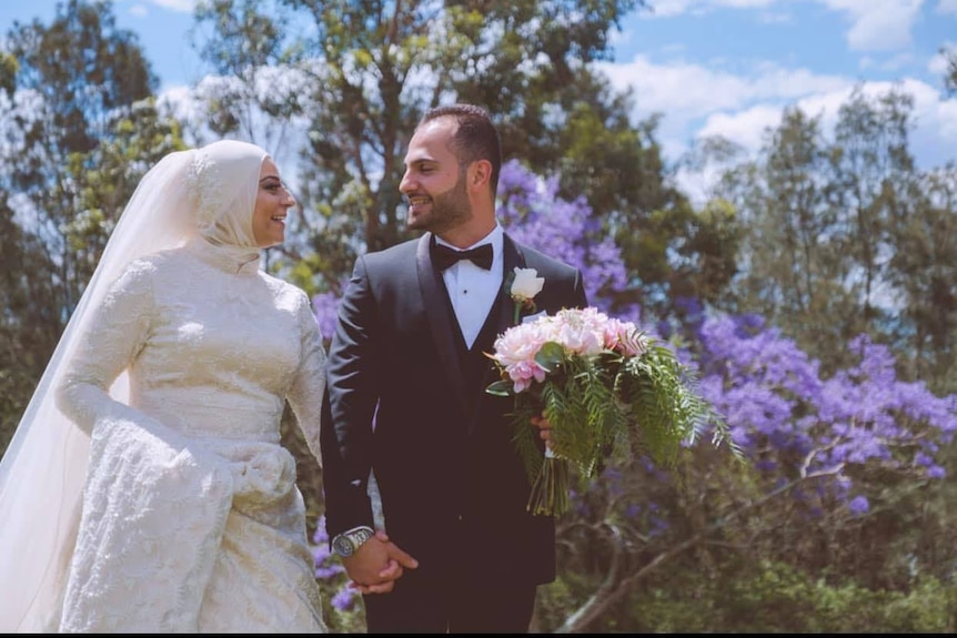 Man in suit and woman in white dress holding hands and getting married