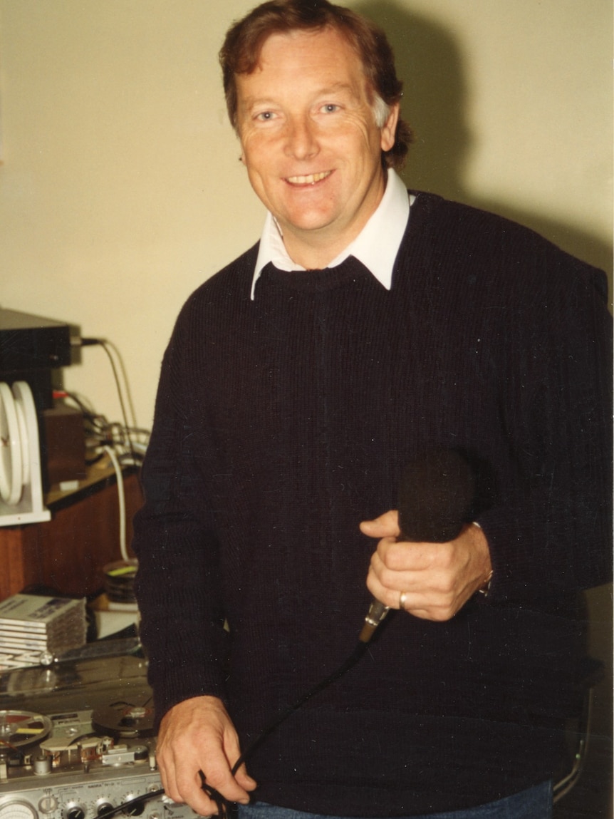 Mike Pritchard holding microphone in old radio studio.