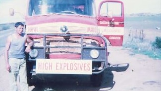 A man leaning on a truck with a high explosives sign on the front