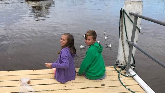 Two kids sitting on a dock.