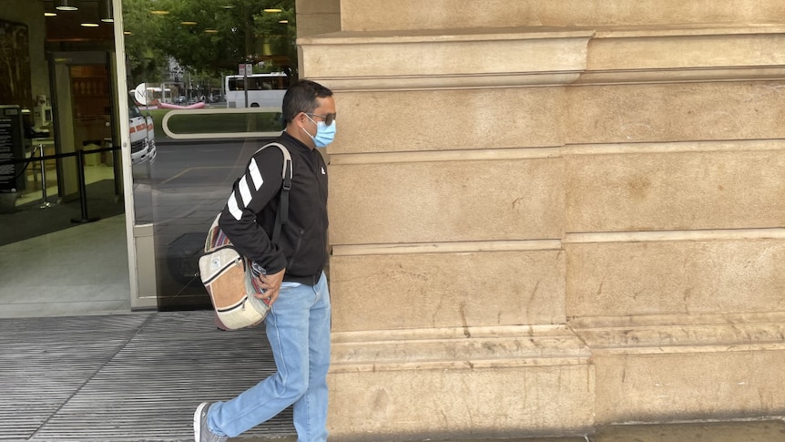 Arjun Kandel leaves the District Court wearing sunglasses and a mask.