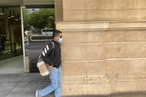 Arjun Kandel leaves the District Court wearing sunglasses and a mask.