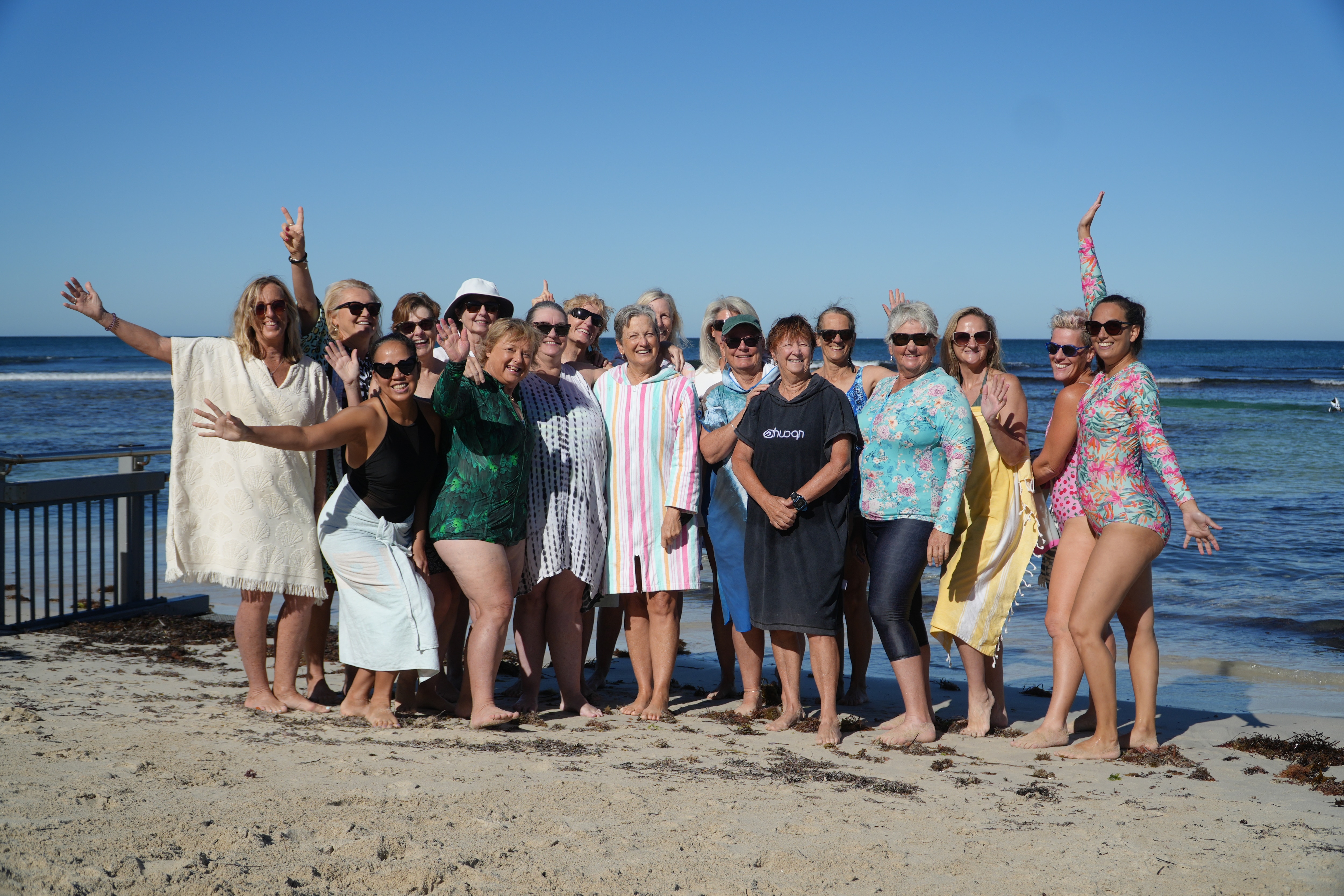 Grupo de mulheres sorrindo perto da praia.