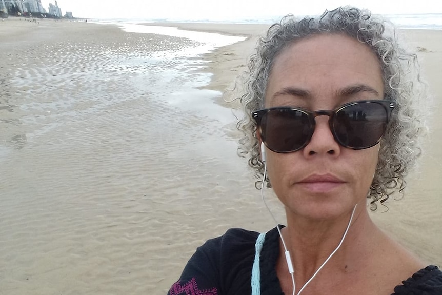 Woman in sunnies and curly grey hair on beach