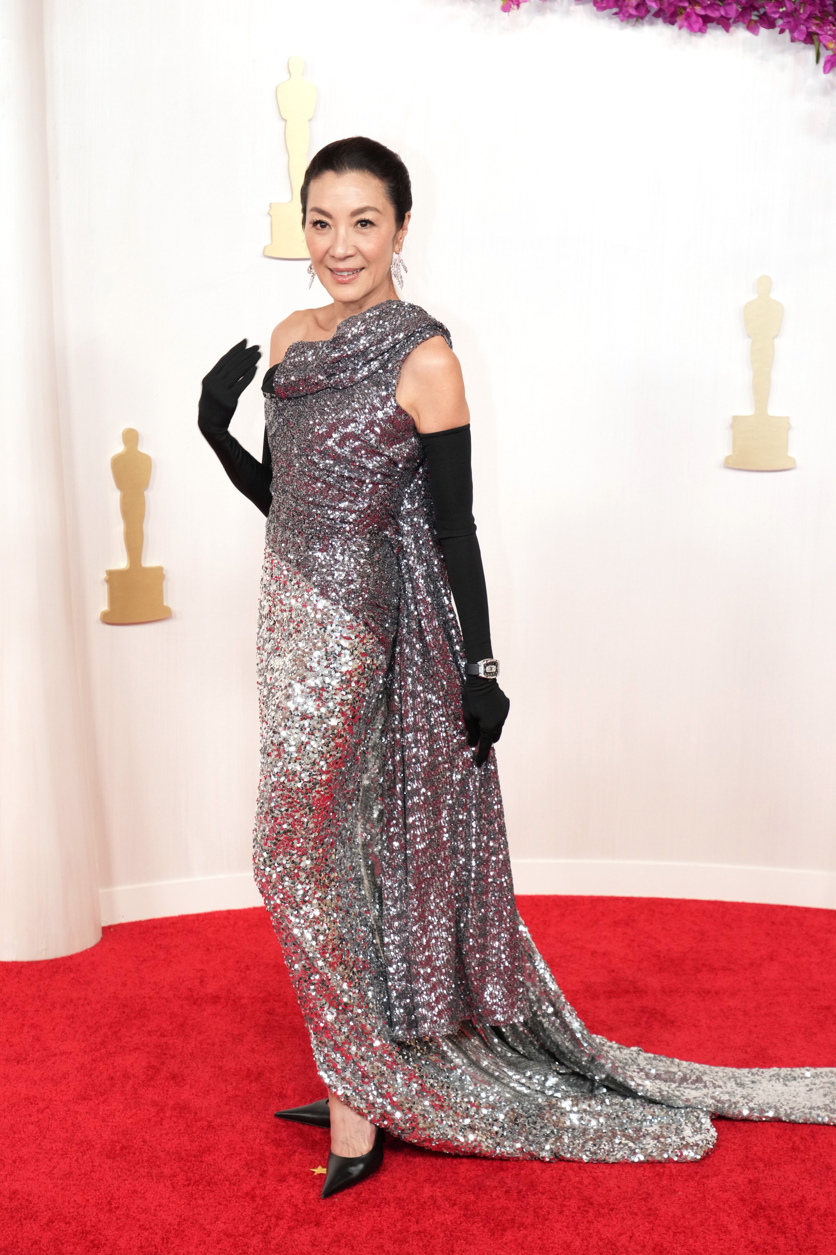 Michelle Yeoh in a shimmery silver dress with black arm sleeves on