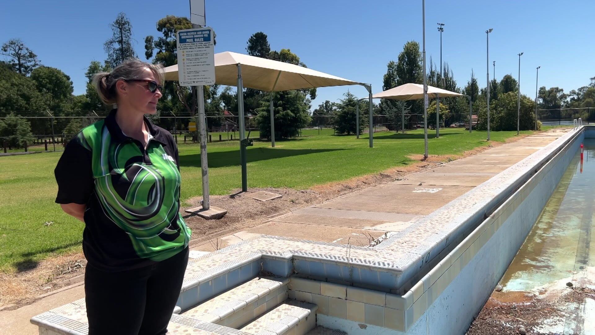 A lady looks out over a dilapidated pool
