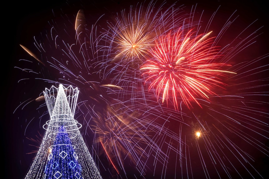 Fireworks light the sky above an illuminated Christmas tree at the Cathedral Square.