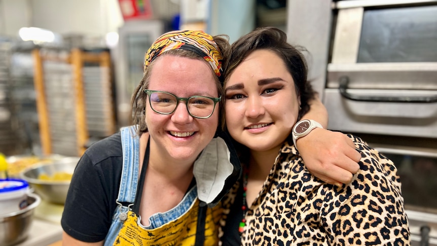 Two women hug in a kitchen