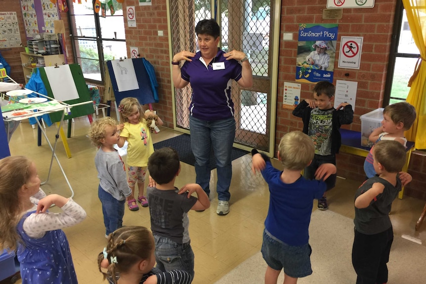 Teacher Therese Tessier plays 'heads, shoulders, knees and toes' with children.