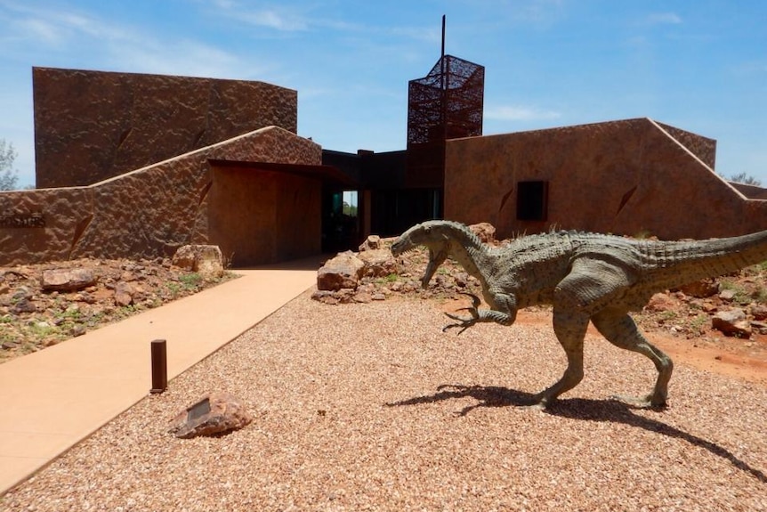 The cement-rendered Age of Dinosaurs Museum with a dinosaur out the front