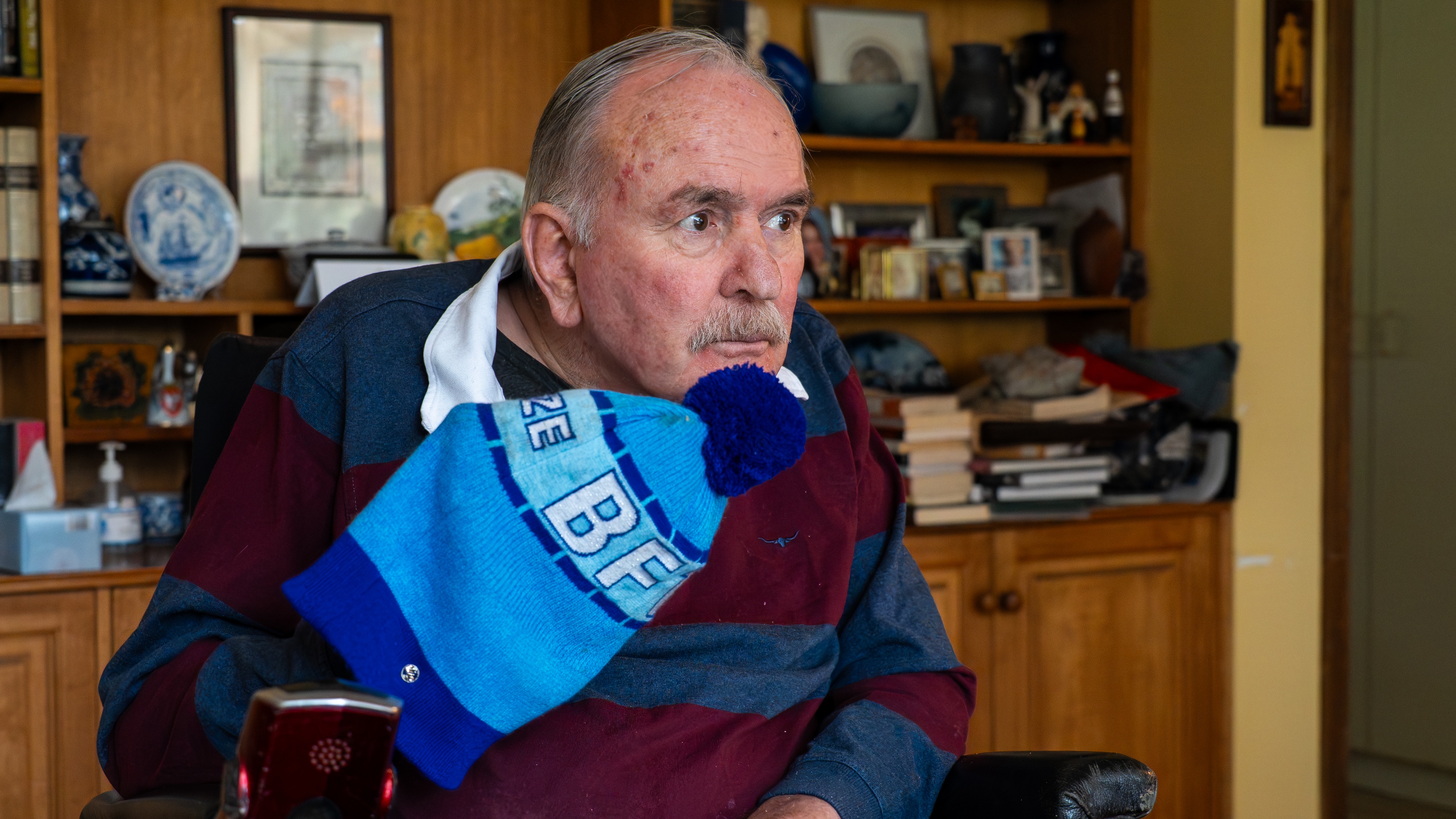 a man in a wheelchair holding a blue beanie