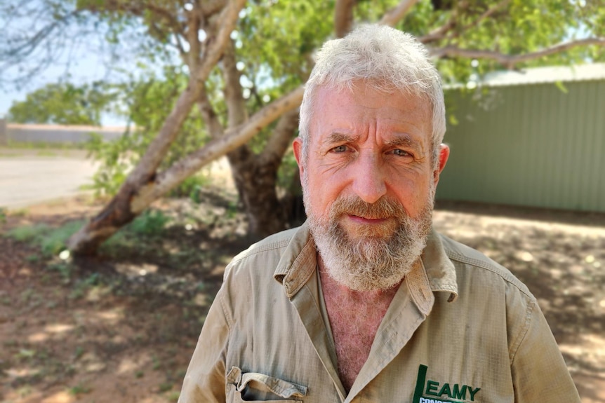 A man in a khaki shirt staring down the barrel of the camera