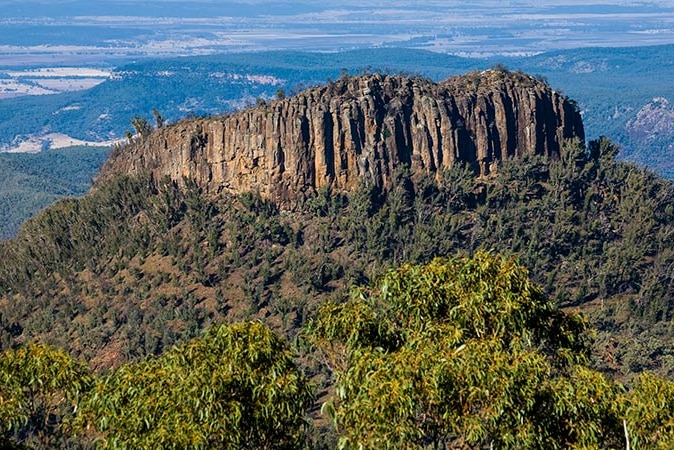 A photo of a mountain with a rocky top and lush base in Mount Kaputar National Park