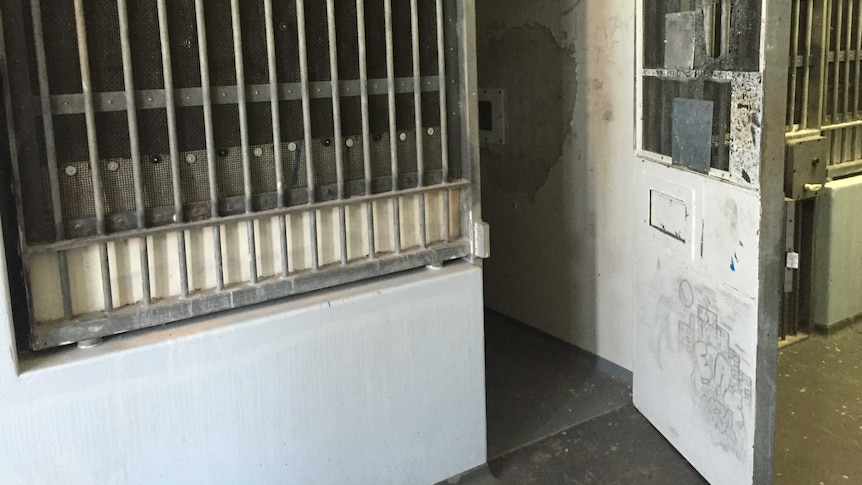 A graffitied door opens to a cell inside the Don Dale Youth Detention Centre.