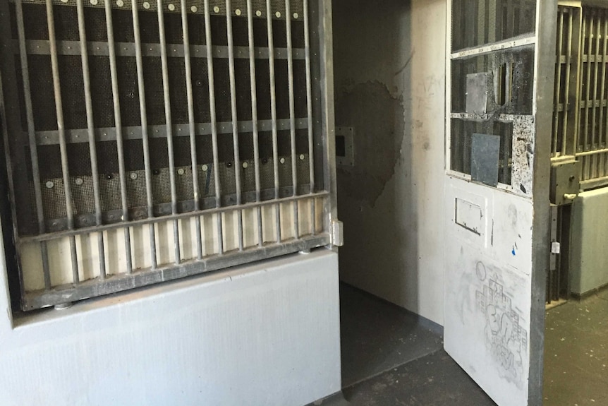 A graffitied door opens to a cell inside the Don Dale Youth Detention Centre.