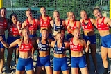 Smiling women wearing athletic wear on a beach court.