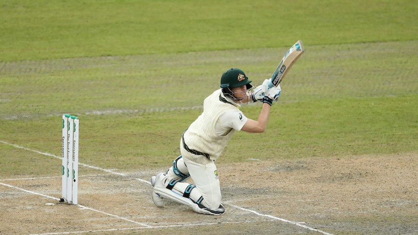 Steve Smith holds his bat up at the 45 degree angle while on his knees after playing a shot